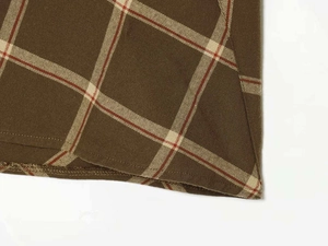 Detailed view of dark coffee and red plaid fabric showing twill weave and neat hemline