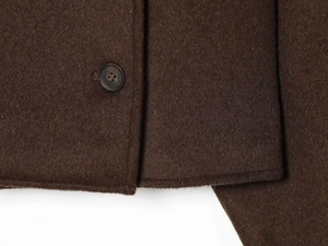 Gros plan détaillé de la veste en laine marron chocolat montrant la texture et le bouton