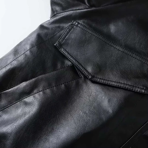 Macro detail of black leather jacket featuring double-stitching and flap pocket texture
