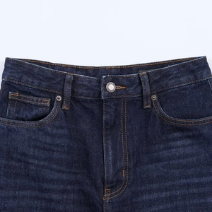 Close-up of waist detailing and orange stitching on vintage dark blue denim jeans