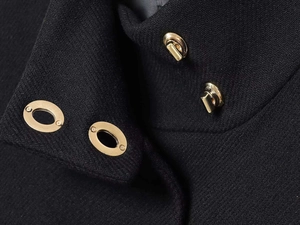 Detalle de chaqueta de lana negra con cuatro hebillas de metal dorado en el cuello