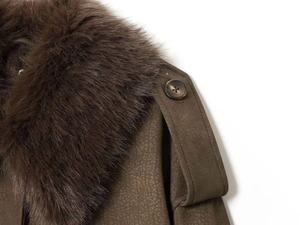 Détail d'une veste vert militaire avec un col en fausse fourrure et patte d'épaule