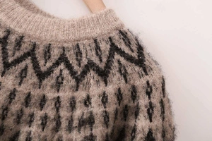 Detail of light brown knit sweater with black geometric jacquard and fuzzy texture