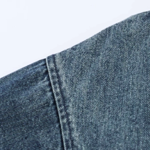 Dettaglio delle doppie cuciture e trama denim lavato sulla giacca blu