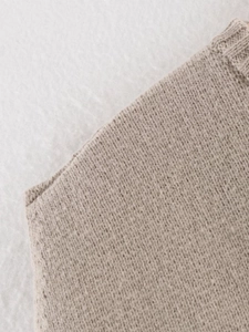 Close-up of oatmeal sleeveless knit vest showing ribbed edge texture and stitching detail