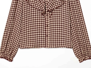 Close-up of red and beige gingham shirt with ruffled collar and button detail