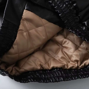 Close-up of black leather jacket with brown diamond-quilted lining and elastic hem