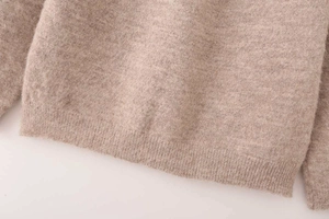 Detail view of the ribbed hem and soft brushed texture on this light brown knit sweater