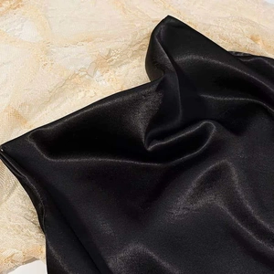Detailed macro view of black satin fabric with contrasting cream floral lace trim