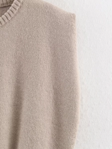 Close-up of the ribbed crewneck and fine knit texture on a beige sleeveless vest