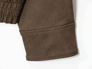 Détail des poignets côtelés et de l'ourlet sur une veste vintage en similicuir marron