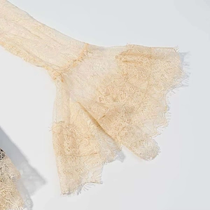 Close-up detail of cream lace bell sleeves with delicate eyelash trim embroidery