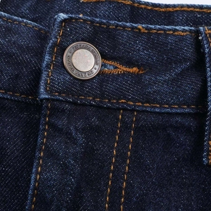Macro detail of high-density denim waist with vintage metal button and contrast stitching
