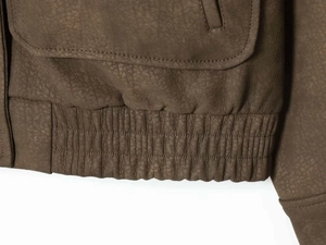 Détail de la veste en cuir marron avec ourlet élastique et rabat de poche