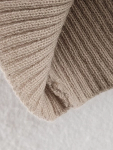 Detailed close-up showing beige rib-knit fabric texture and high-quality stitching detail