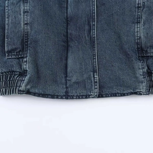 Dettaglio della giacca di jeans blu con cuciture a contrasto e bordo a costine