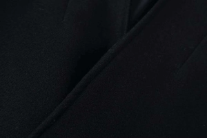Detailed close-up of high-quality black wool fabric texture and fine stitching on a coat