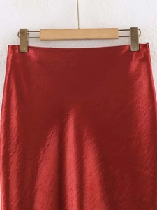 Detail shot of elegant dark red satin skirt fabric with smooth silky texture and sheen
