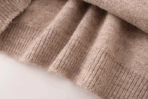 Detailed macro view of soft brown knit fabric with ribbed cuff and warm wool texture