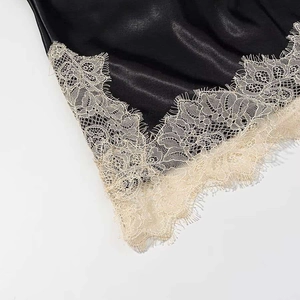 Detailed macro view of black satin hem with delicate champagne eyelash lace trim