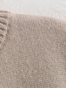 Detailed macro view of the ribbed neckline and knit texture on this sleeveless apricot vest