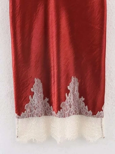 Detail of red satin skirt featuring a delicate white eyelash lace trim at the hemline
