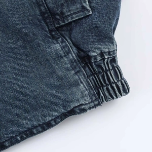 Dettaglio giacca di jeans blu scuro con trama lavata e cuciture sull'orlo elastico