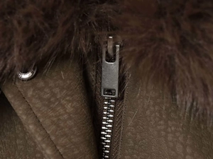 Détail de la fermeture éclair en métal sur une veste marron avec col en fausse fourrure