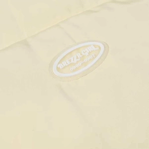 Detailed macro view of the Brezza Girl brand logo patch on beige winter jacket fabric