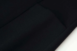 Detail of premium black woolen coat showing high-quality pocket stitching and fabric texture