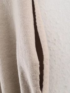 Detail view of the soft knitted texture and pocket seam on this beige sleeveless vest