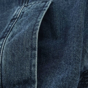 Vista macro del tessuto denim blu scuro con finitura stonewashed su una giacca corta