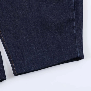 Detail of dark blue denim fabric with high-quality orange stitching on the hem and corners