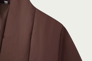 Detailed close-up of dark brown quilted puffer jacket with high-quality stitching