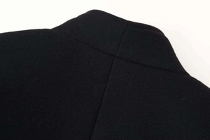 Macro view of solid black wool fabric texture and clean seam stitching on the collar