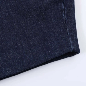 Detailed close-up of dark blue snow-wash denim fabric with professional stitched seams