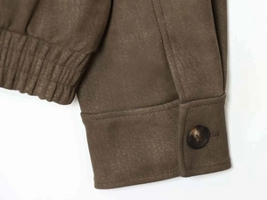 Détail du poignet d'une veste marron avec bouton en résine et ourlet élastique ajusté