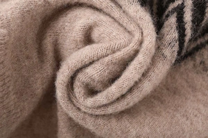 Macro shot of khaki knit fabric featuring soft texture and black geometric patterns