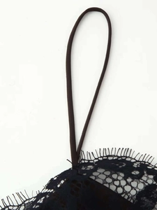 Detail de la dentelle cils et des fines bretelles en maille sur une robe en satin noir