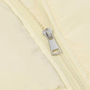 Close-up of a silver metal zipper on a cream winter jacket with matching smooth fabric