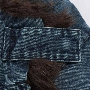 Dettaglio del tessuto denim blu con bordo in ecopelliccia marrone e cuciture rinforzate