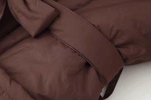 Macro view of dark brown quilted cotton coat fabric with belt detail and stitching
