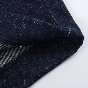 Close-up of high-quality dark blue denim fabric showing neat overlock stitching details