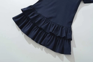 Detail view of the navy blue dress featuring a double-layered ruffled hem and knit texture