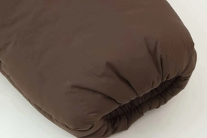 Detail of a brown quilted puffer jacket featuring elastic cuffs and satin finish texture