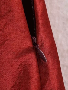 Close-up of the high-quality invisible zipper on a silky dark red satin midi skirt