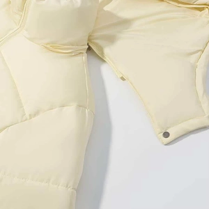 Detail of cream quilted puffer jacket featuring smooth zipper and metallic snap button