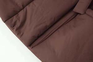 Detail of solid dark brown quilted coat showing texture, stitching and soft padding quality