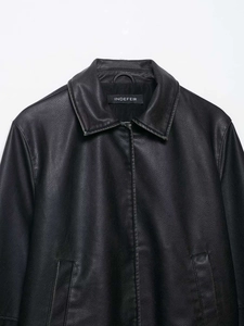 Detail shot of black faux leather jacket texture and classic lapel collar close-up