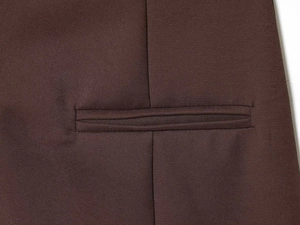 Detail of dark brown puff sleeve dress showing textured twill fabric and welt pocket